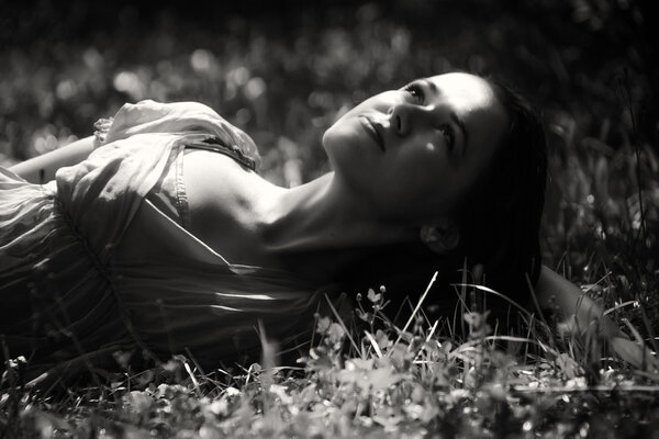 Brunette lying in the grass.Black and white