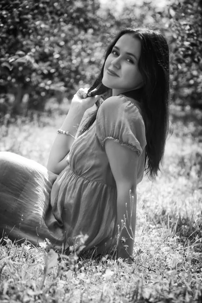 Bruneta sedí v trávě — Stock fotografie