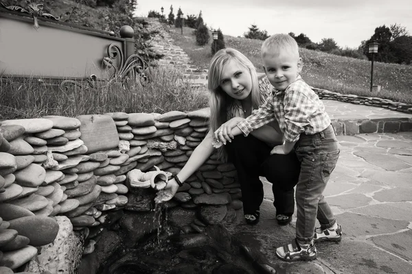 Moeder met zoon in de buurt van de bron van water — Stockfoto