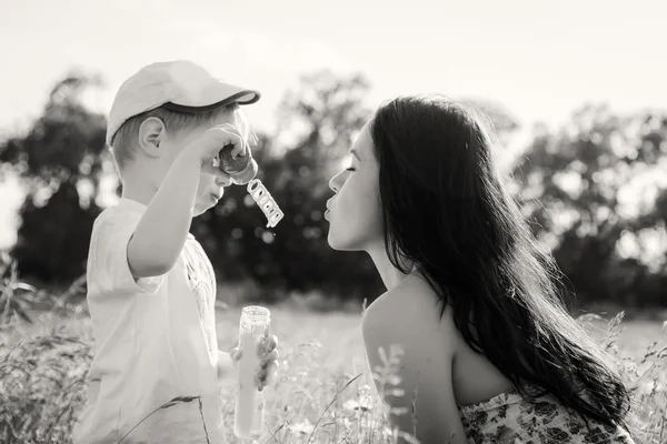 Mutter spielt mit Sohn mit Seifenblasen — Stockfoto