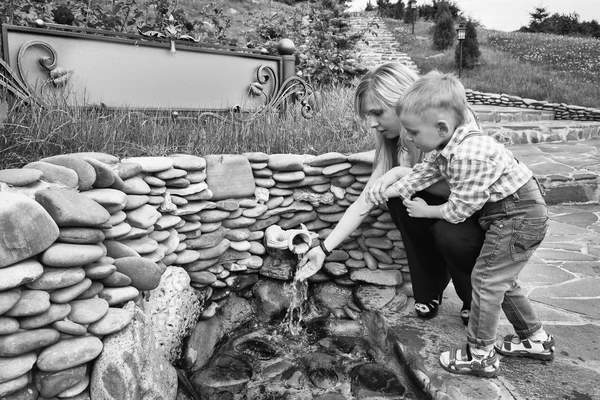 Moeder met zoon in de buurt van de bron van water — Stockfoto