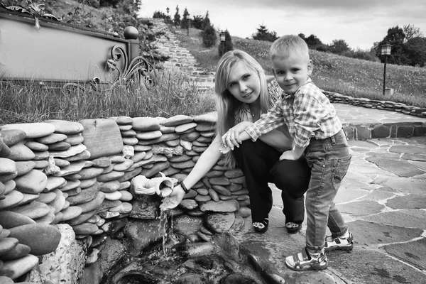 Mamma med son nära källan till vatten — Stockfoto