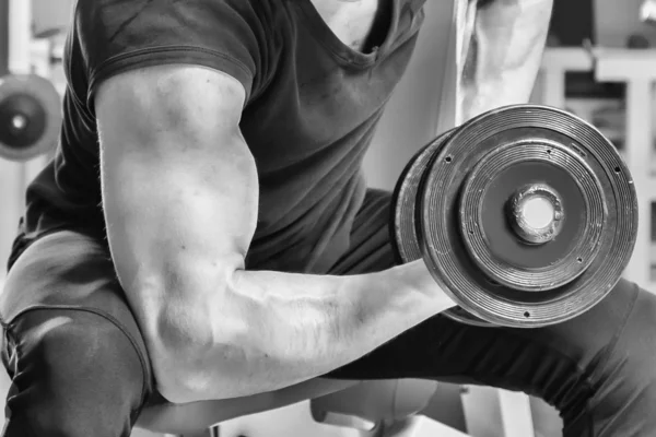 Homem faz exercícios com halteres . — Fotografia de Stock