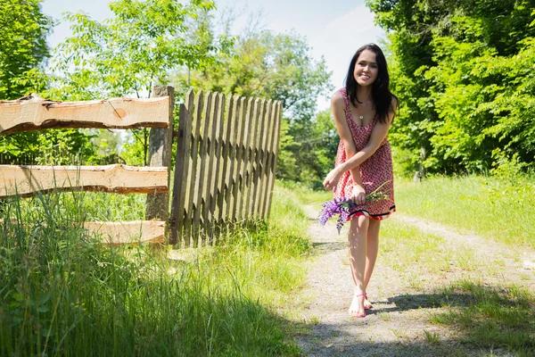 Mujer caminando con flores — Foto de Stock