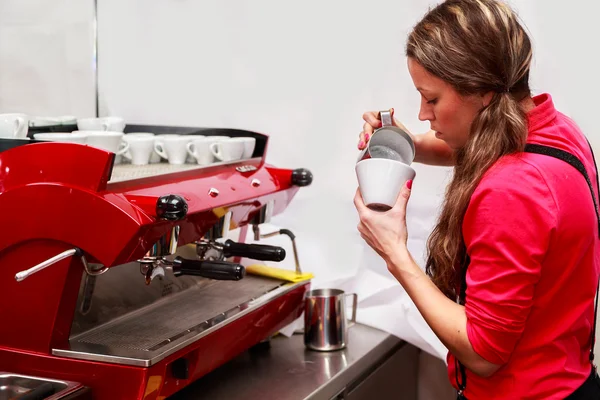 Servitrisen hälla mjölk att göra cappuccino — Stockfoto