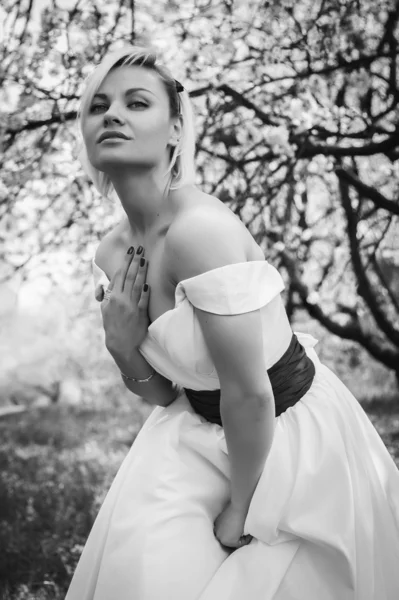 Blonda în rochie albă în grădina de primăvară — Fotografie, imagine de stoc