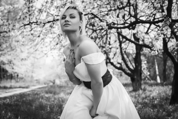 Loira em vestido branco no jardim da primavera — Fotografia de Stock