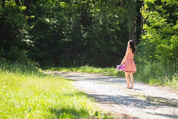 Vrouw wandelen met bloemen — Stockfoto