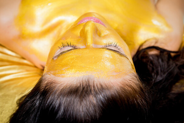 Девушка делает золотую маску
