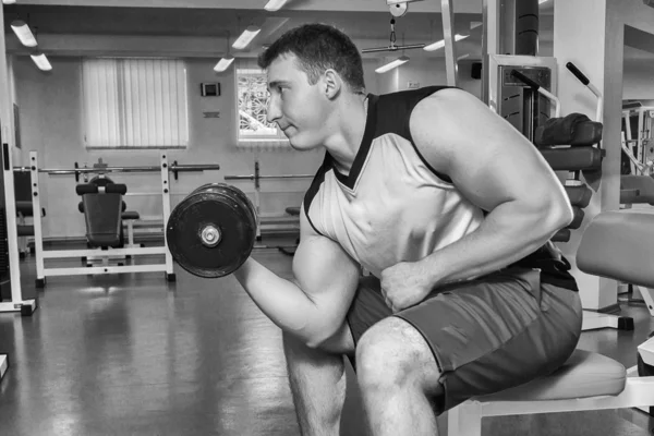 Homem faz exercícios com halteres . — Fotografia de Stock