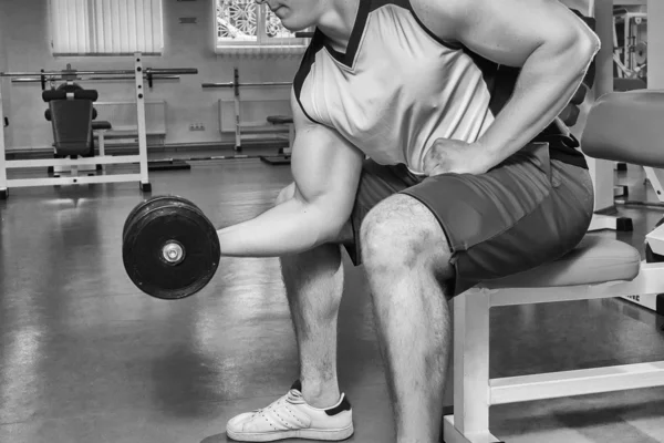 Homem faz exercícios com halteres . — Fotografia de Stock