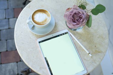 Tablet masada, çiçekler de bir kafede.