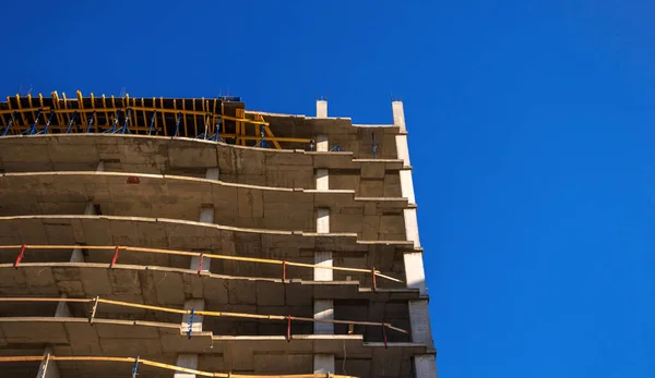 Bau eines modernen Gebäudes. Wohnhaus im Bau vor blauem Himmel Hintergrundbild — Stockfoto