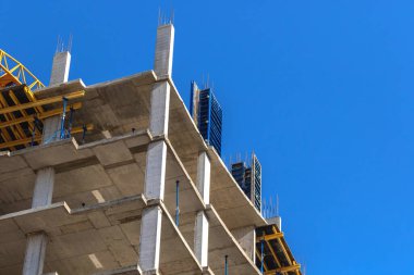 Yeni çok katlı konutların inşaat alanının çatısı. Endüstriyel yapı, endüstri ekipmanları ve beton duvarlar mavi gökyüzü arkaplan fotoğrafına karşı