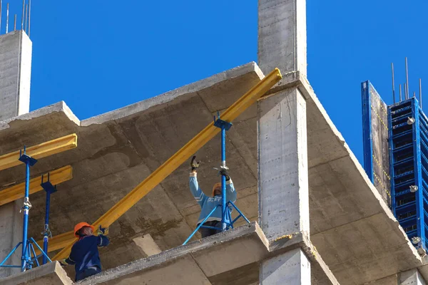 Bauarbeiter auf einem im Bau befindlichen Hochhaus vor blauem Himmel — Stockfoto