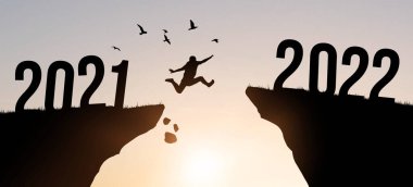 2021 ile 2022 yılları arasında uçan kuşlarla uçan genç adam. Akşam renkli gökyüzü. Yeni yıl konsepti 