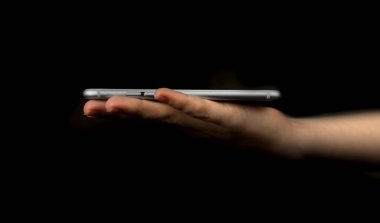 Siyah arka planda cep telefonu olan bir kadın. Modern teknoloji, web ağı vs. için sunum, model ve şablon kavramı.