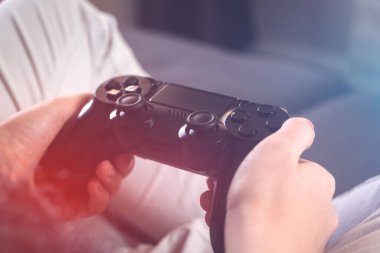 Kadın eller oyun kontrolörünü tutuyor. Büyük televizyonlu modern akış ve oyun kavramı evde, kanepede oturuyor.