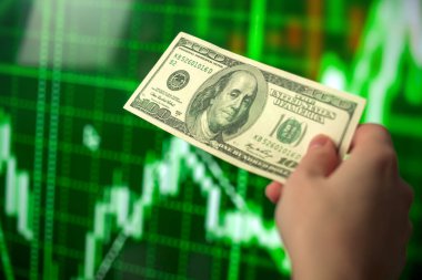 İş yatırımı ve borsa. Yeşil hisse senedi finansal grafikleri üzerinde el ele tutuşan dolar banknotu. Ekonomik büyüme, döviz kuru kavramı