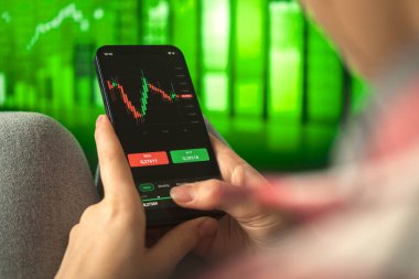 Kadınlar evde otururken mobil hisse senedi uygulaması kullanıyor. Akıllı telefon uygulaması ile eski ticaret. Borsa grafikli ekran, çift pozlama işi ve yatırım konsepti geçmişi 