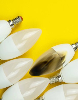 Yangından sonra kırılmış modern LED ampul, kısa devre konsepti. Ev güvenliği. Üst görünüm, kopyalama alanı, sarı arkaplan fotoğrafı