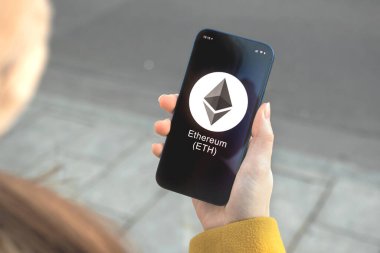 Ethereum ETH şifreleme sembolü, logo. İş ve finansal konsept. Akıllı telefon ile el, kripto simgesi ile ekran kapatma
