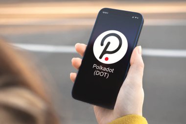 Polkadot DOT kripto para birimi sembolü, logo. İş ve finansal konsept. Akıllı telefon ile el, kripto simgesi ile ekran kapatma