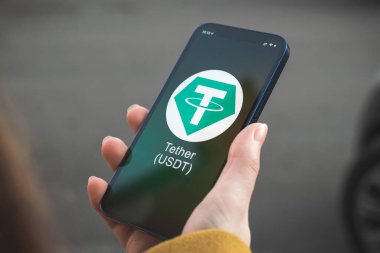 USDT şifreleme sembolü, logo. İş ve finansal konsept. Akıllı telefon ile el, kripto simgesi ile ekran kapatma