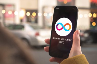 İnternet Bilgisayar ICP kripto para birimi sembolü, logo. İş ve finansal konsept. Akıllı telefon ile el, kripto simgesi ile ekran kapatma