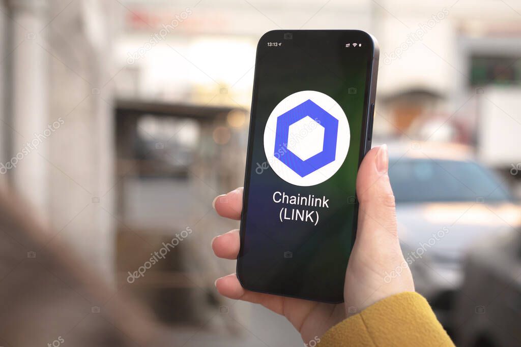 Chainlink cryptocurrency symbol, LINK logo. Business and financial concept. Hand with smartphone, screen with crypto icon closeup