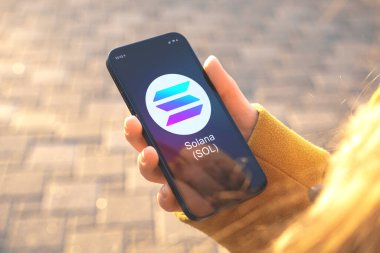 Solana SOL şifreleme sembolü. İş ve finansal konsept. Akıllı telefonlu el, kripto logolu ekran yakın plan