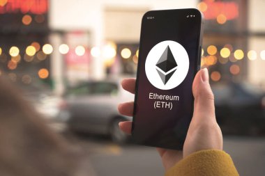 Ethereum ETH şifreleme sembolü, logo. İş ve finansal konsept. Akıllı telefon ile el, kripto simgesi ile ekran kapatma