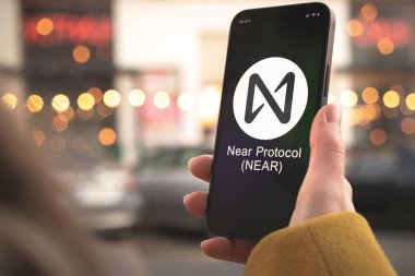 Protokol kripto para birimi sembolü logonun yanında. İş ve finansal konsept. Akıllı telefon ile el, kripto simgesi ile ekran kapatma