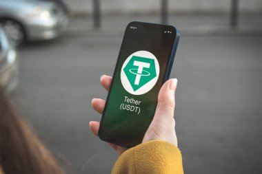 USDT şifreleme sembolü, logo. İş ve finansal konsept. Akıllı telefon ile el, kripto simgesi ile ekran kapatma