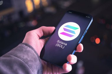 Solana SOL şifreleme sembolü, logo. İş ve finansal konsept. Akıllı telefon ile el, kripto simgesi ile ekran kapatma
