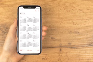 Kharkov, Ukrayna - 17 Kasım 2021: Apple iPhone ekranında takvim 2022 uygulaması. Ahşap arkaplan
