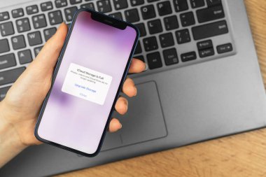Kharkov, Ukrayna - 21 Kasım 2021: Elmalı iPhone ve iCloud 'lu kadın ekranda uzay dışı mesajı. İş yeri, ahşap masa, üst manzara.