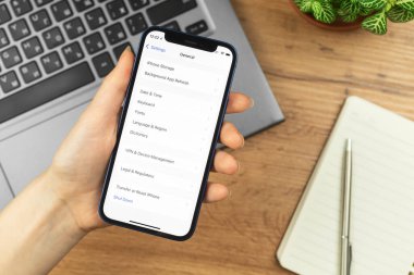 Kharkov, Ukrayna - 21 Kasım 2021: Kadın Apple iPhone 'da genel ekranı açtı. İş yeri, ahşap masa, üst manzara.