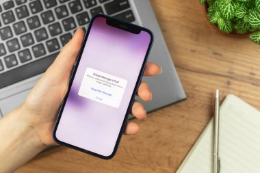 Kharkov, Ukrayna - 21 Kasım 2021: Kadın iCloud ile Apple iPhone 'u ücretsiz uzay ekranından uzak tutun. İş yeri, ahşap masa, üst manzara. 