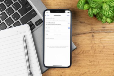 Kharkov, Ukrayna - 21 Kasım 2021: Apple iPhone 'da Ödeme Yöntemi ekran, cep telefonu banka kartı ayarları. İş yeri, ahşap masa, üst manzara. 