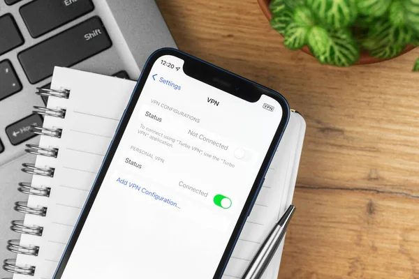 Kharkov, Ukrayna - 21 Kasım 2021: Apple iPhone 'daki VPN ayarları. İş yeri, ahşap masa, üst manzara.