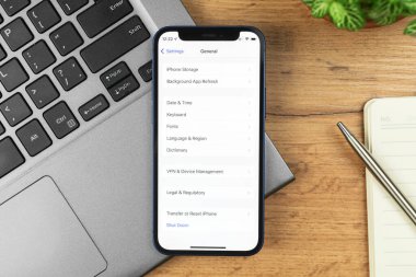 Kharkov, Ukrayna - 21 Kasım 2021: Apple iPhone 'daki genel ayarlar. İş yeri, ahşap masa, üst manzara. 
