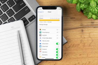 Kharkov, Ukrayna - 21 Kasım 2021: iCloud Apple iPhone 'dan çıktı, tam depolama ayarları. İş yeri, ahşap masa, üst manzara. 