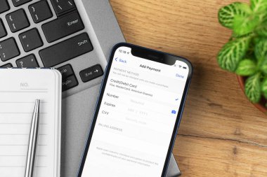 Kharkov, Ukrayna - 21 Kasım 2021: Apple iPhone 'a Ödeme Yöntemi ekleyin, ayarlar. İş yeri, ahşap masa, üst manzara.