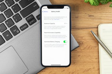 Kharkov, Ukrayna - 21 Kasım 2021: Apple iPhone 'da Pil Sağlık Ekranı. İş yeri, ahşap masa, üst manzara. 