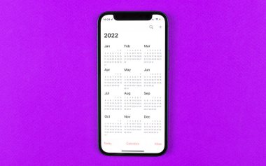 Kharkov, Ukrayna - 17 Kasım 2021: Apple iPhone ekranında 2022 takvimi. Takvim uygulaması. Mor arkaplan, iş alanı, üst görünüm 