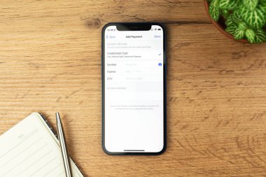 Kharkov, Ukrayna - 21 Kasım 2021: Apple iPhone 'da Ödeme Yöntemi Ekle. Ahşap masa arkaplanı 