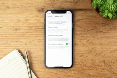 Kharkov, Ukrayna - 21 Kasım 2021: Apple iPhone 'da Pil Sağlık Ekranı. Ahşap masa arkaplanı