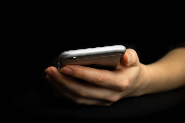 Person uses mobile phone, front view. Black background, hand and smartphone close-up. High tech, technology and communication concept