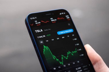 Kharkov, Ukrayna - 1 Aralık 2021: Tesla Inc. TSLA hisse senedi kapanışı. Finansal grafikler, yatırım, dijital bankacılık konsepti. Elinde borsa uygulaması olan akıllı telefon. 